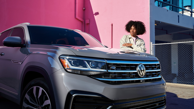 This is an exterior shot of the 2020 Atlas Cross Sport, V6 SEL Premium R-Line 4MOTION, showing talent admiring parked Atlas Cross Sport. 